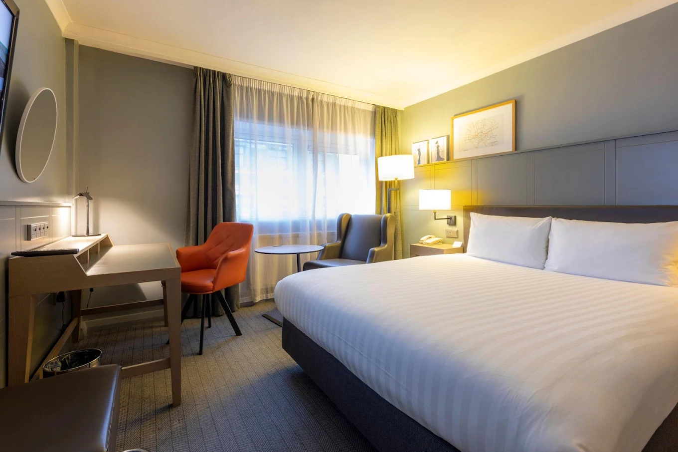 Holiday Inn London Regent's Park king guest room with large bed, orange armchair, desk and framed London Underground map artwork