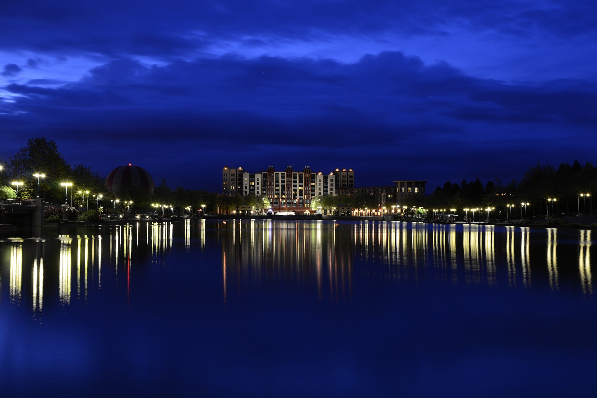 Lights of Disney Village reflected in the lake at Disneyland Paris after sunset
