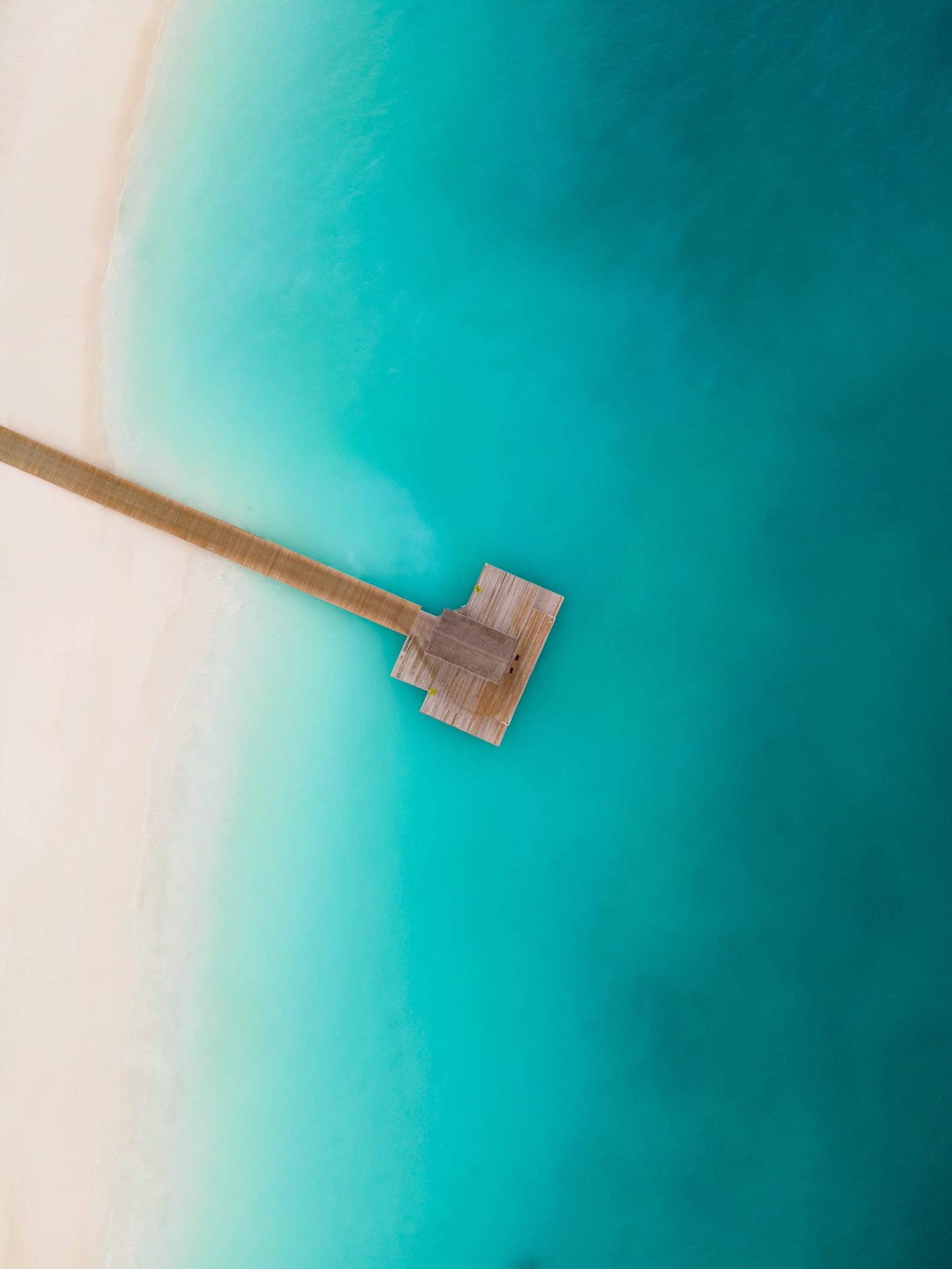 Aerial view of Sun Siyam Iru Veli island in Dhaalu Atoll, Maldives, with overwater suites reaching into the lagoon