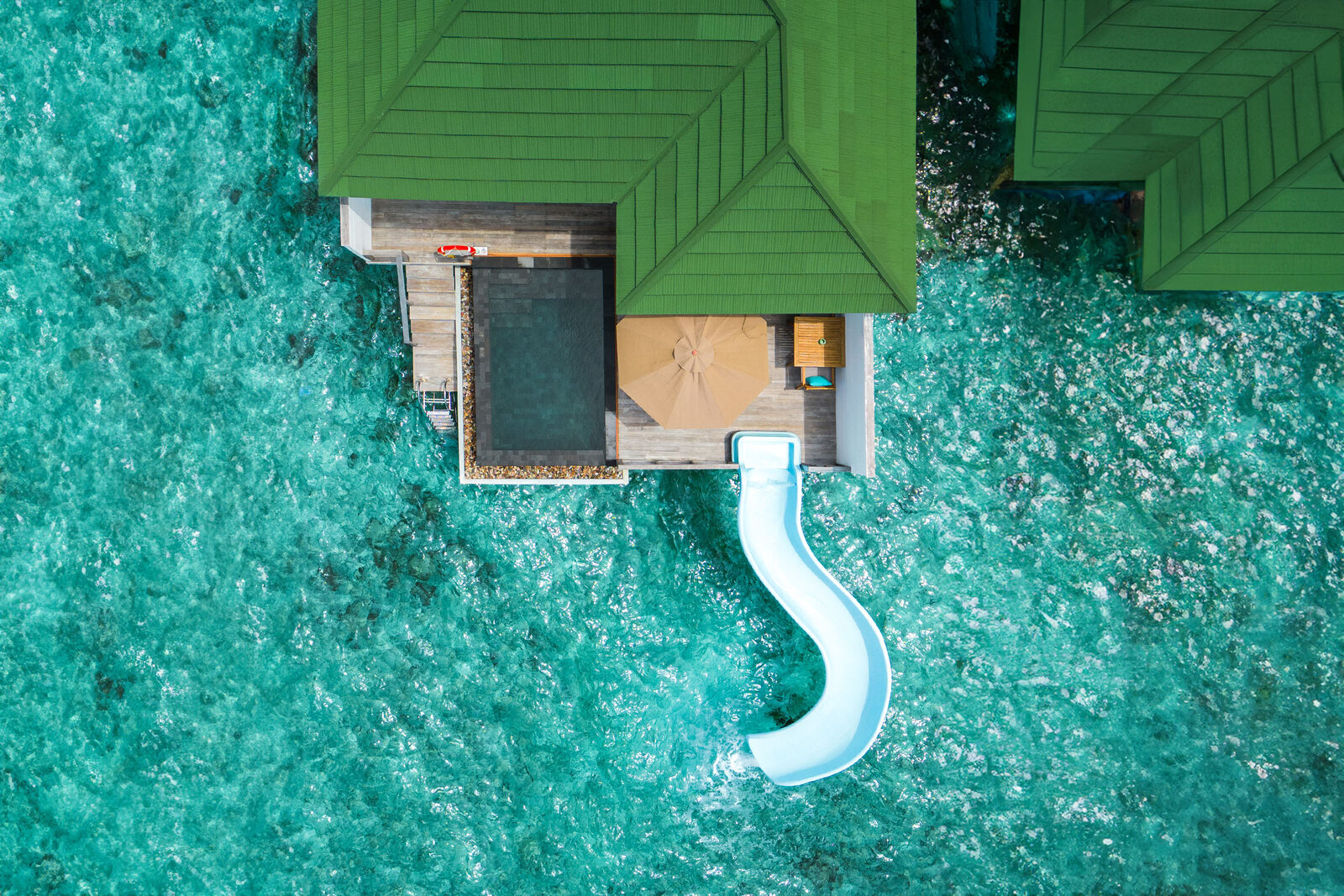 Aerial view of a lagoon villa with pool and slide at Siyam World Maldives