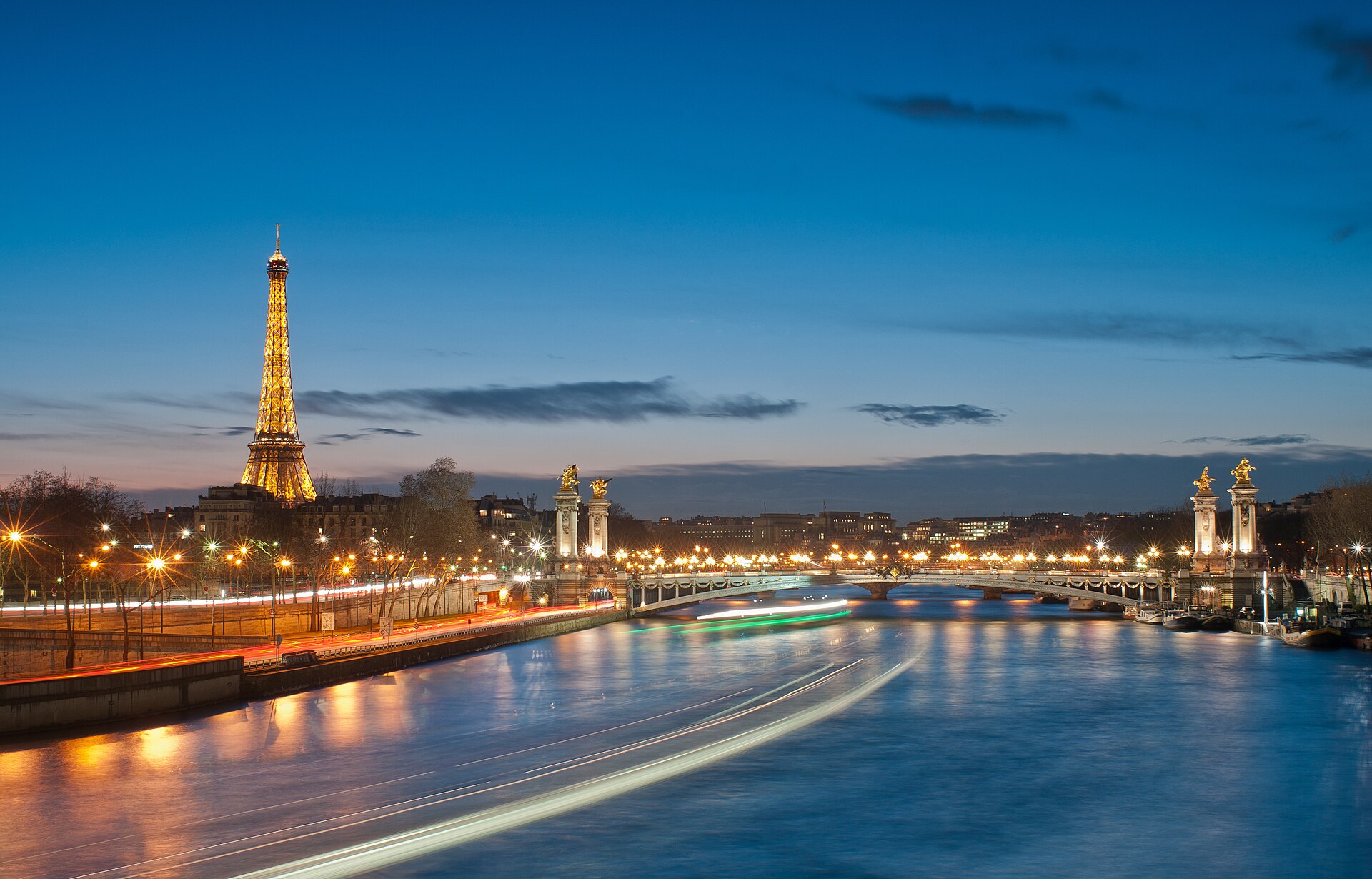 The Eiffel Tower and Pont Alexandre III illuminated at night over the Seine
