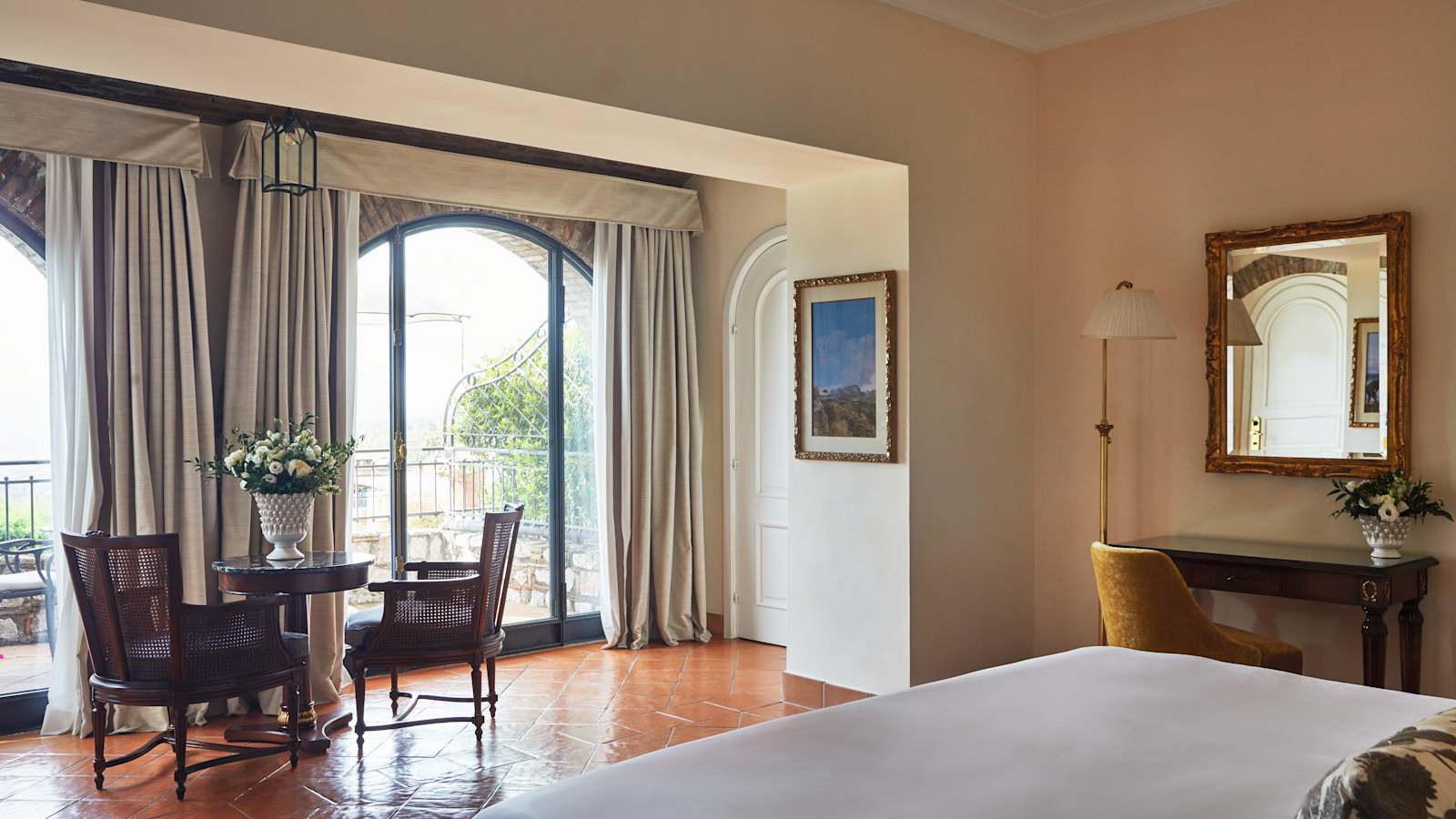 Sea-view room at Grand Hotel Timeo Taormina with arched French doors to a private terrace, terracotta floor and antique furniture