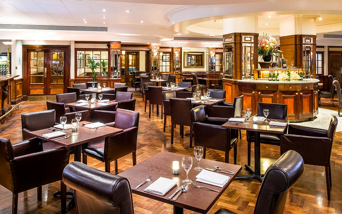 Brasserie Restaurant and Bar at Copthorne Tara Hotel London Kensington with laid tables, banquette seating and a bar counter
