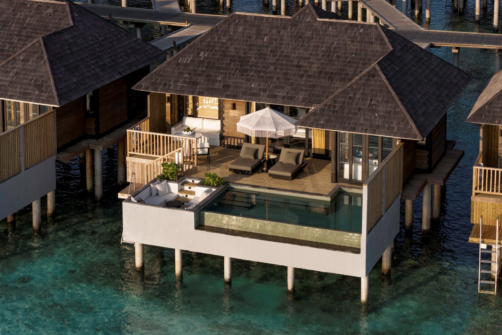 Aerial view of a Sun Siyam overwater water villa with private infinity pool above the turquoise Maldivian lagoon
