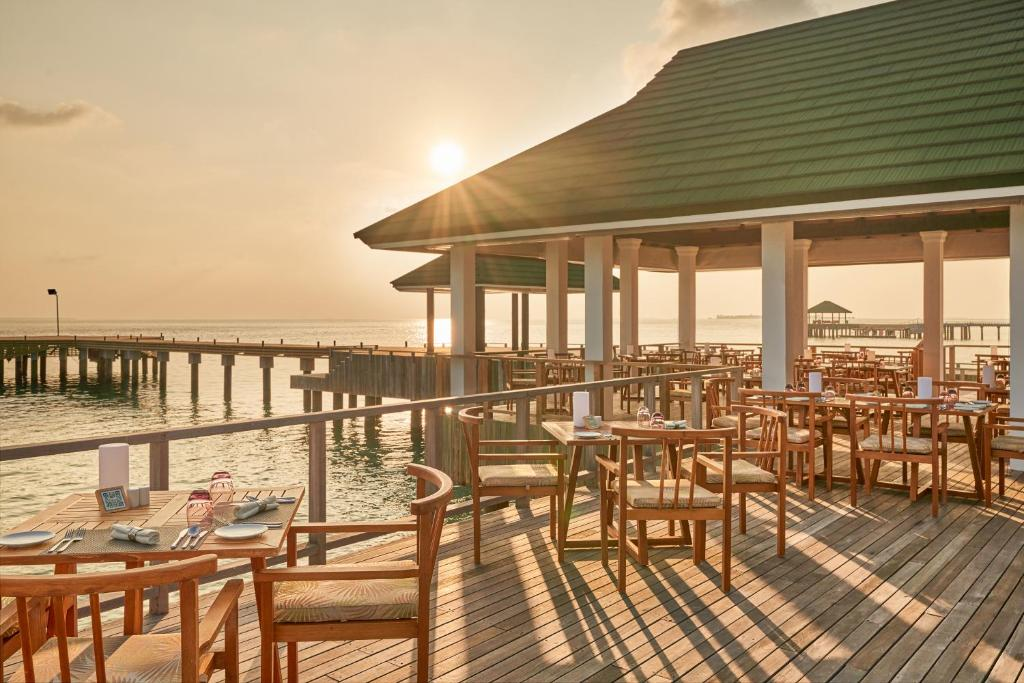 Overwater restaurant at Siyam World Maldives at sunset with wooden deck extending across the lagoon