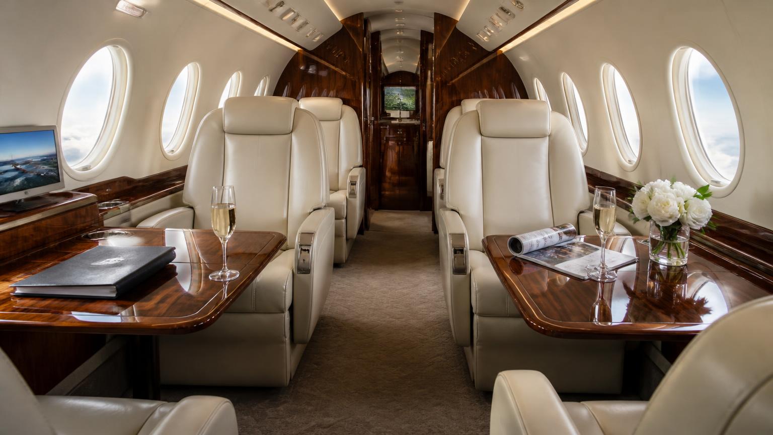 Cream leather club seats and polished walnut tables inside a midsize private jet cabin