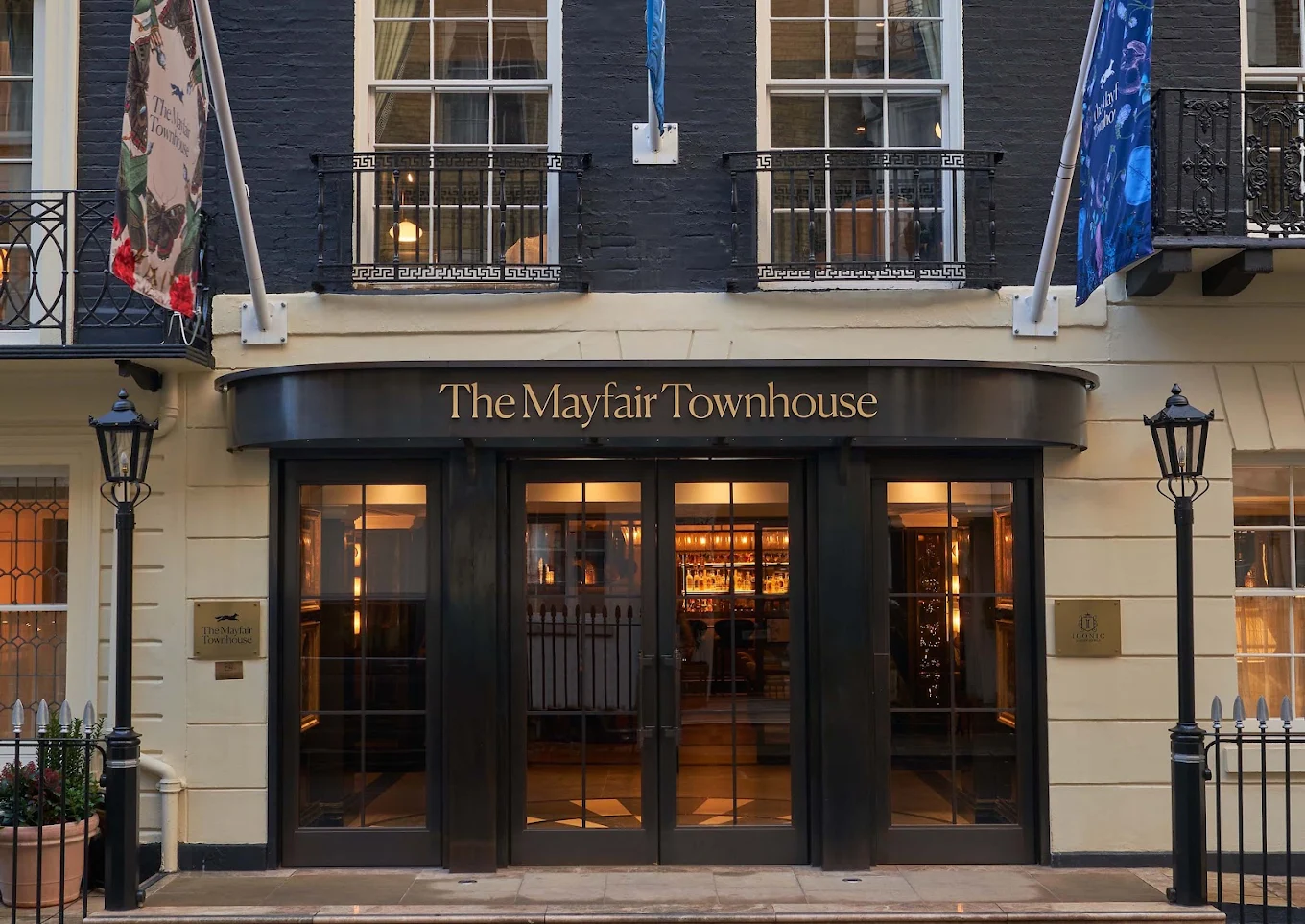 The Mayfair Townhouse hotel entrance on Half Moon Street, London — black-painted Georgian facade with signature banners, glass canopy and vintage lamp posts