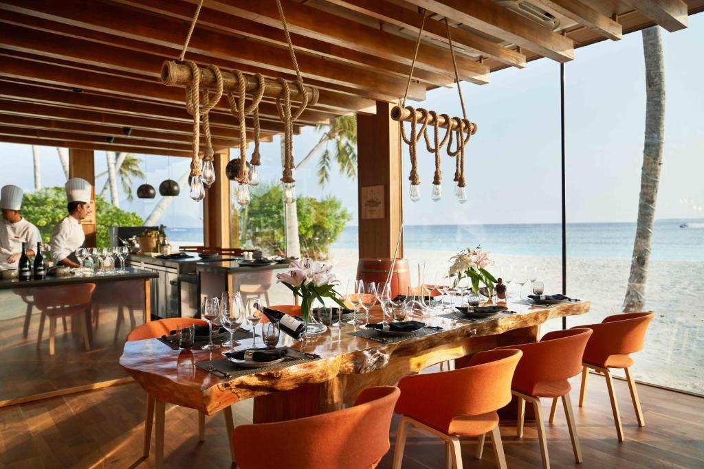 Chef's table at Siyam World Maldives with a live-edge wooden table, hanging rope lamps and open kitchen facing the beach
