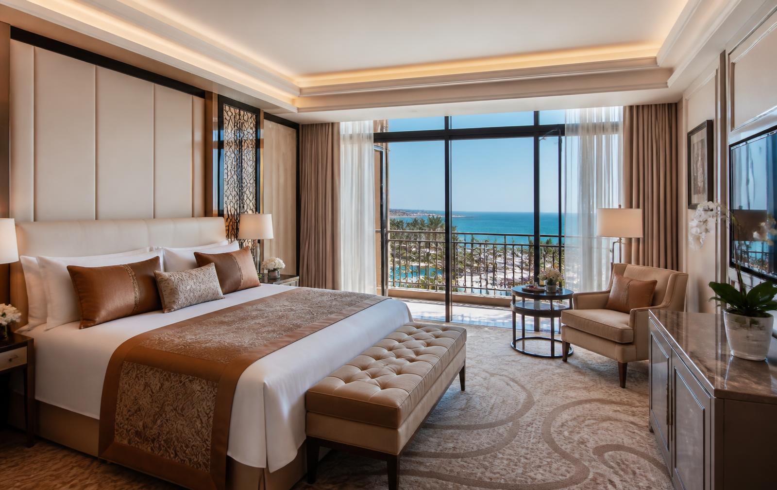 Luxury suite at a five-star Antalya resort with king bed, cream and bronze interiors and a balcony overlooking pools and the Mediterranean